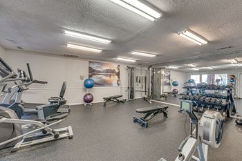 A gym with a variety of equipment including treadmills, exercise balls, and weight machines.